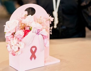 Pink floral arrangement with breast cancer ribbon at a ChicMas Cares event